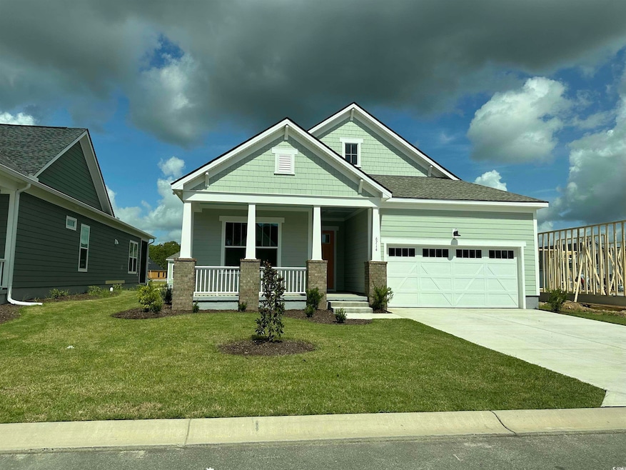 Craftsman-style house with a porch, driveway, a garage, and a front lawn