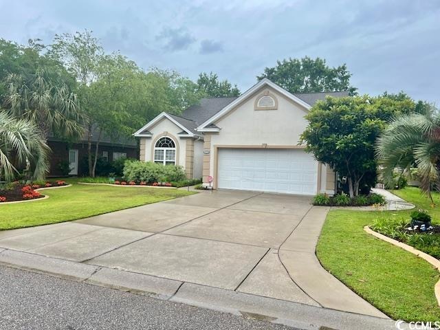 Single story home featuring an attached garage, stucco siding, driveway, and a front yard