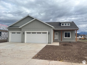 View of front of home with board and batten siding, covered porch, a garage, and concrete driveway