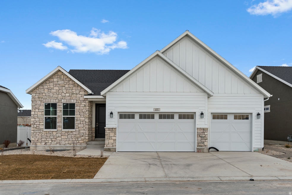 View of front of house featuring stone siding, board and batten siding, concrete driveway, and a garage