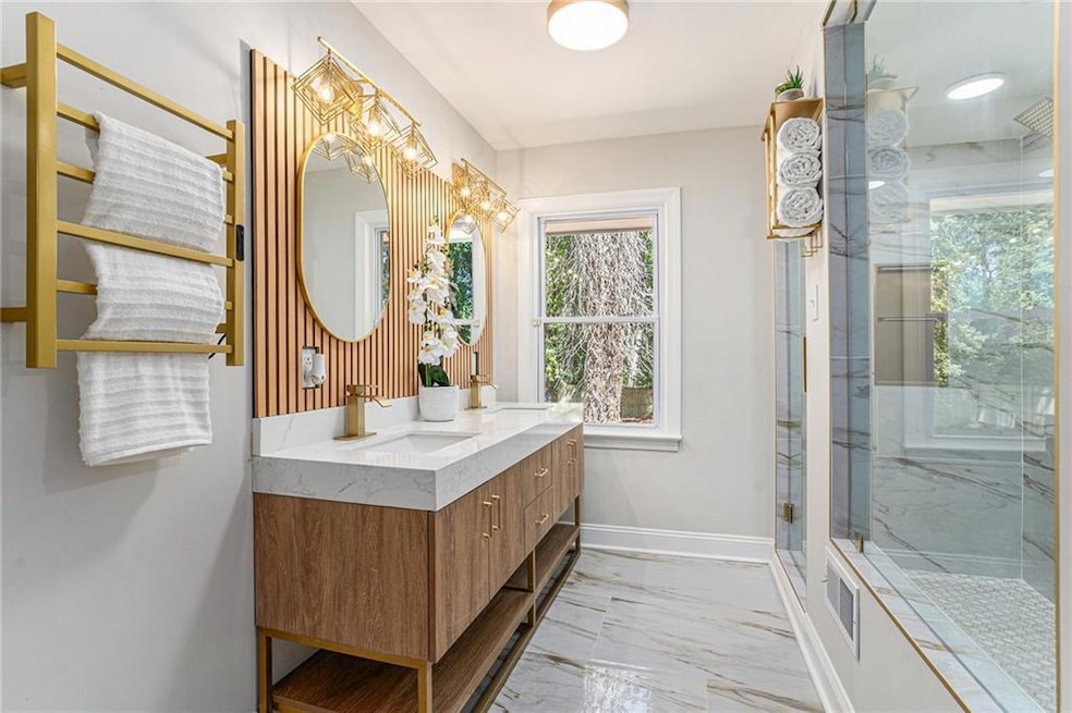Bathroom with light marble finish floors, a marble finish shower, and double vanity