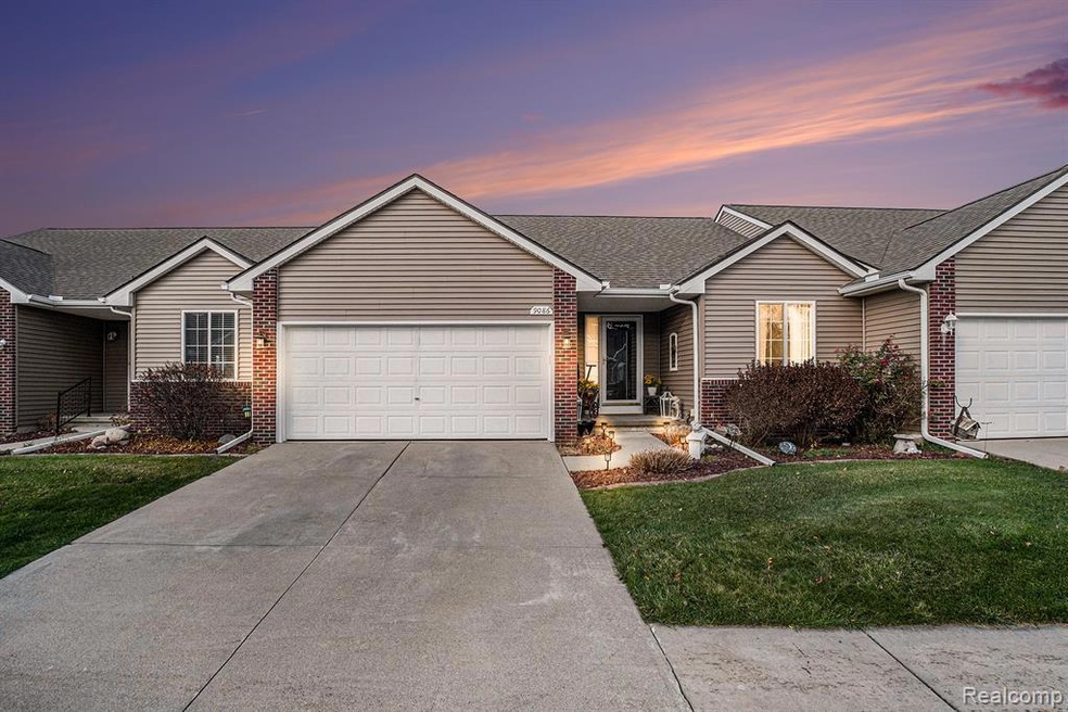 Ranch-style house featuring a front yard, an attached garage, concrete driveway, and roof with shingles