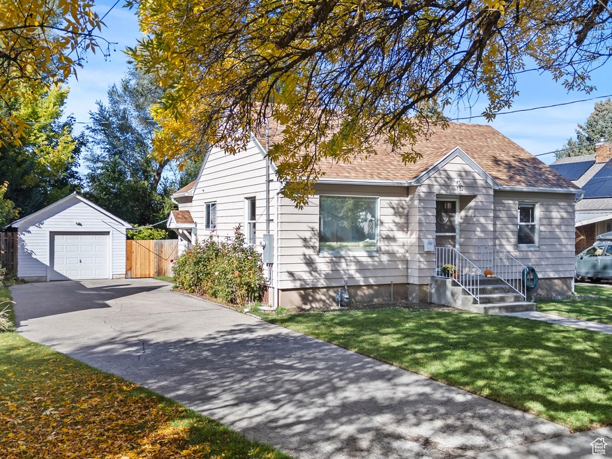 View of front of house featuring an outbuilding, driveway, a detached garage, and a shingled roof