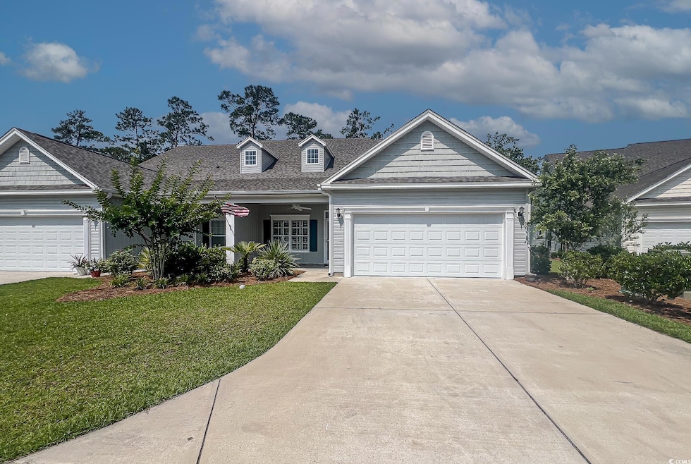 View of front of house with a front yard, driveway, an attached garage, and a shingled roof