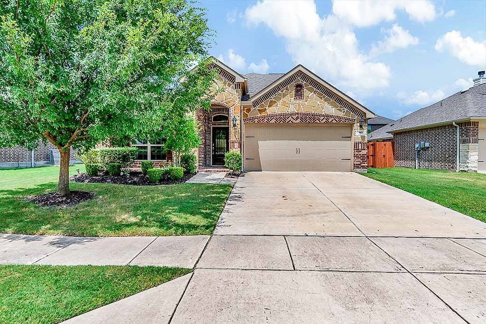 View of front of home with stone siding, brick siding, a garage, and driveway