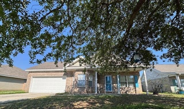 View of front of home featuring an attached garage, concrete driveway, and brick siding