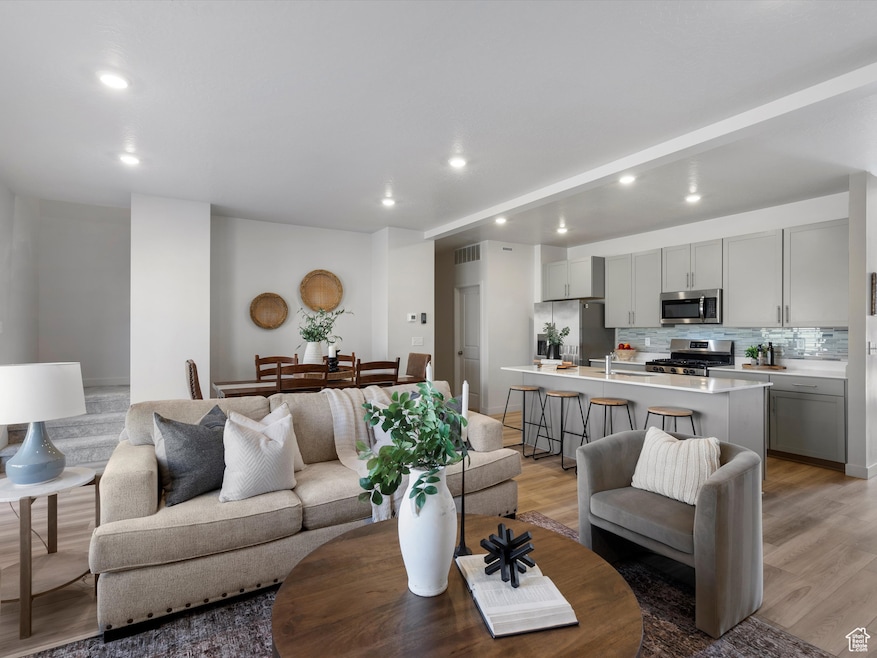 Living room with light wood-type flooring, recessed lighting, and beamed ceiling