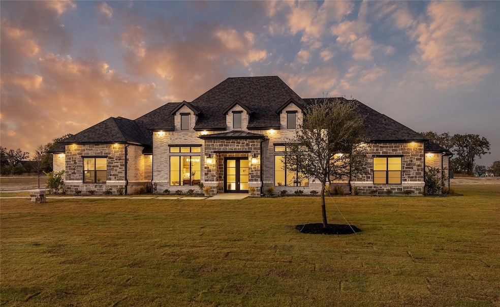 French country inspired facade featuring stone siding, a yard, and a shingled roof