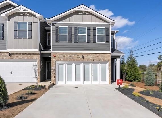 Craftsman house featuring board and batten siding, concrete driveway, a garage, and brick siding