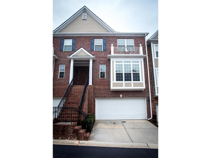 View of front facade featuring concrete driveway, an attached garage, brick siding, and a balcony