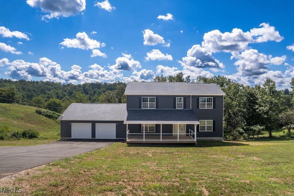 View of front facade featuring a porch, a front yard, driveway, and a garage