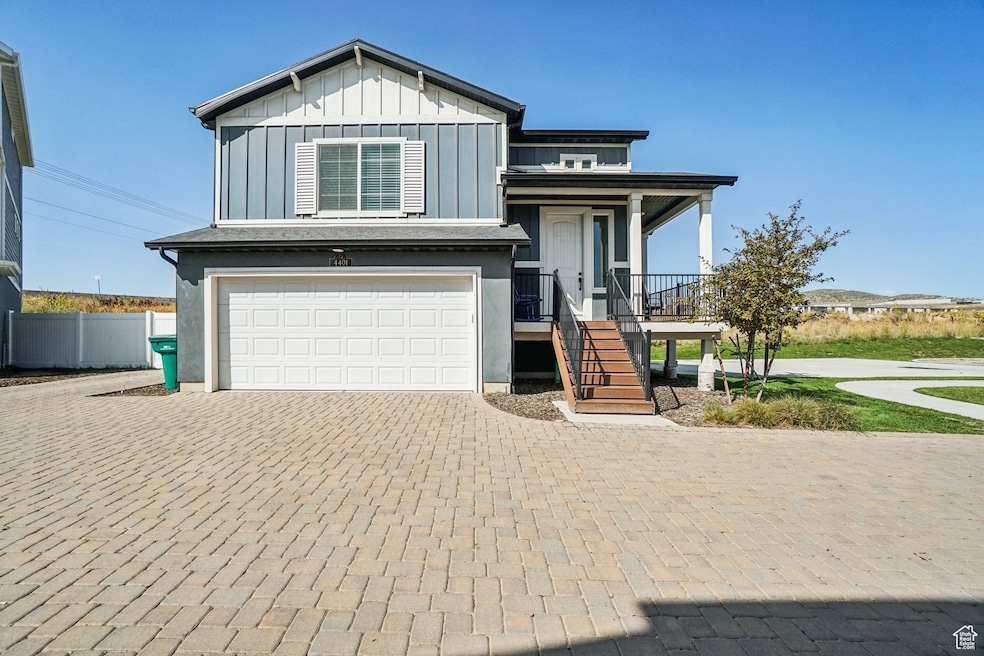 View of front facade featuring a garage, decorative driveway, board and batten siding, stairs, and a porch