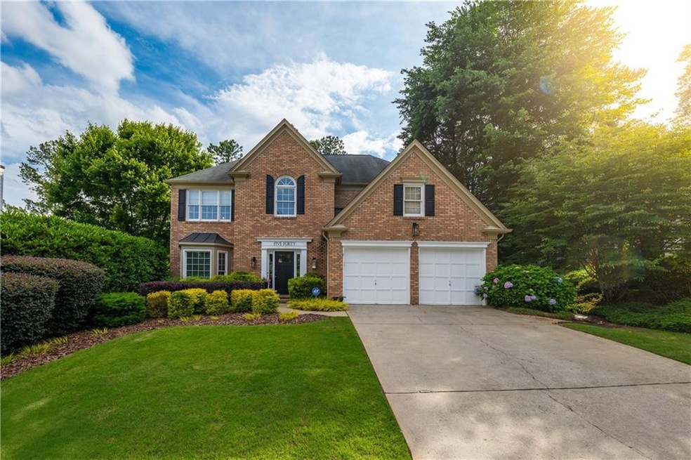 View of front of home with brick siding, driveway, a front yard, and a garage