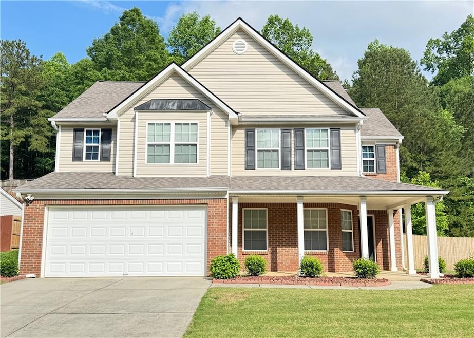 View of front of house with brick siding, covered porch, concrete driveway, and a garage