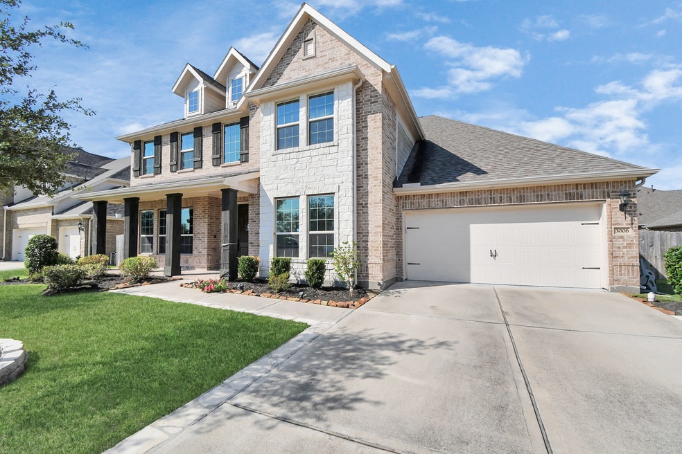 This is a modern two-story home featuring a brick facade, a two-car garage, and a neatly manicured lawn. The covered entryway adds a welcoming touch to the residence.