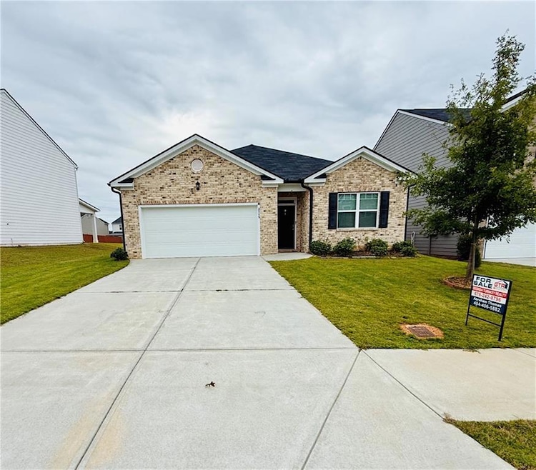 Ranch-style house featuring concrete driveway, a garage, a front yard, and brick siding