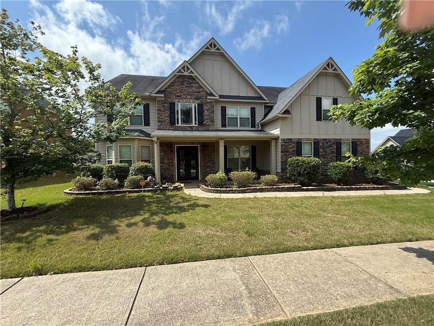 Craftsman-style house featuring board and batten siding, stone siding, and a front yard