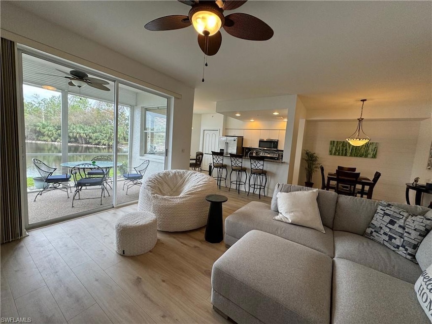 Living room with ceiling fan and light wood-type f