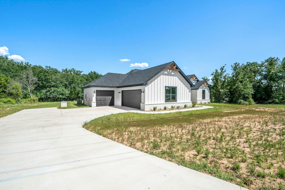 View of front of house with board and batten siding, a front yard, driveway, and a garage
