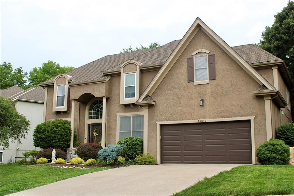 View of front facade with an attached garage, stucco siding, driveway, and a front yard