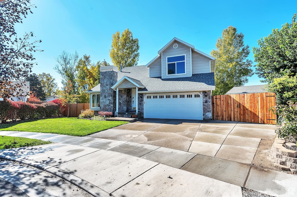 Traditional home featuring concrete driveway, a shingled roof, stone siding, a garage, and a chimney