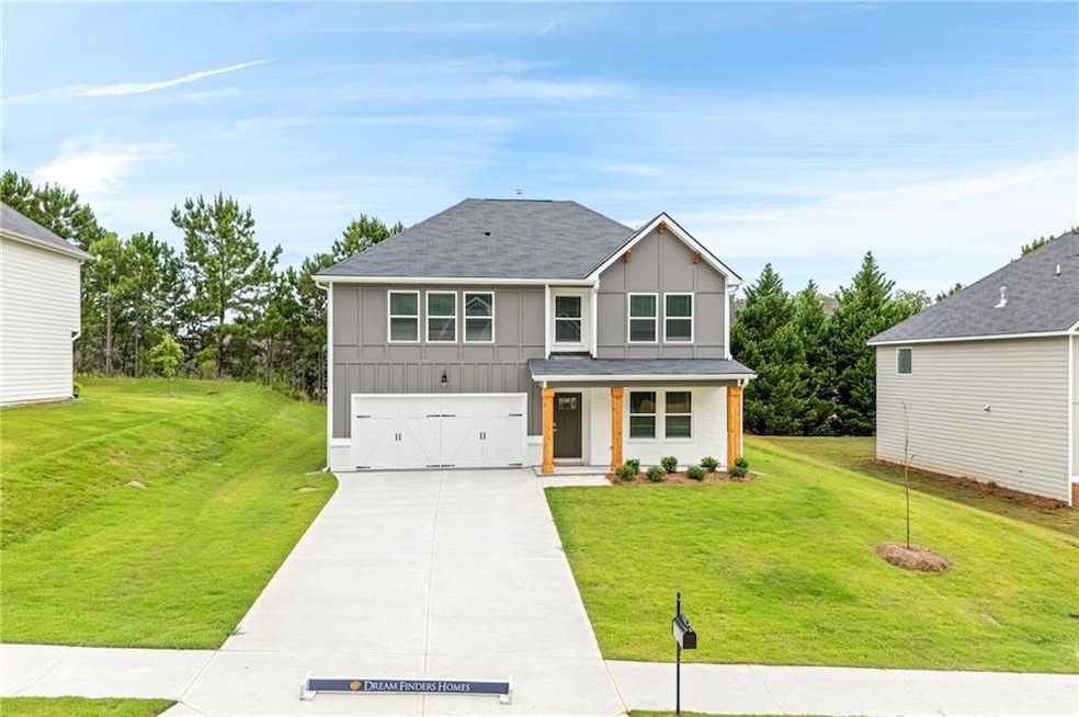 View of front of house featuring a porch, concrete driveway, a front lawn, and an attached garage