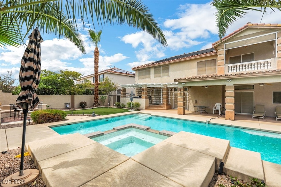 View of pool featuring a patio area, a pool with connected hot tub, a fenced backyard, and a balcony.
