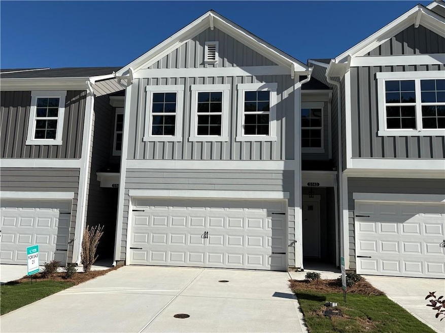 View of front of home with board and batten siding, an attached garage, and driveway