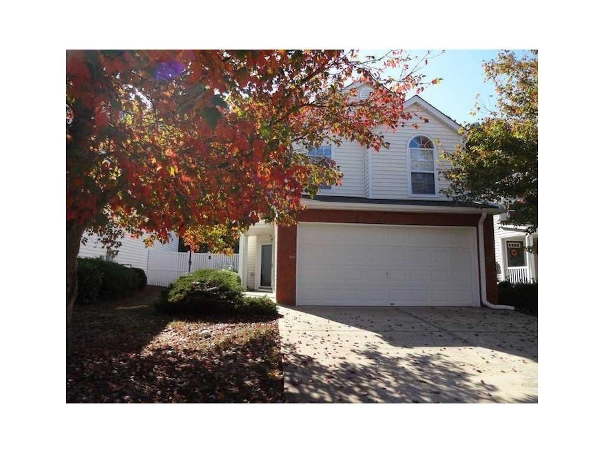 View of property hidden behind natural elements featuring an attached garage and concrete driveway