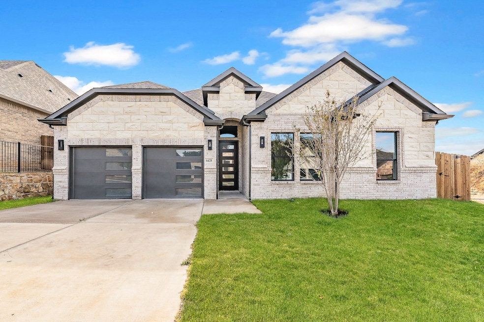 French country home with driveway, an attached garage, brick siding, and stone siding
