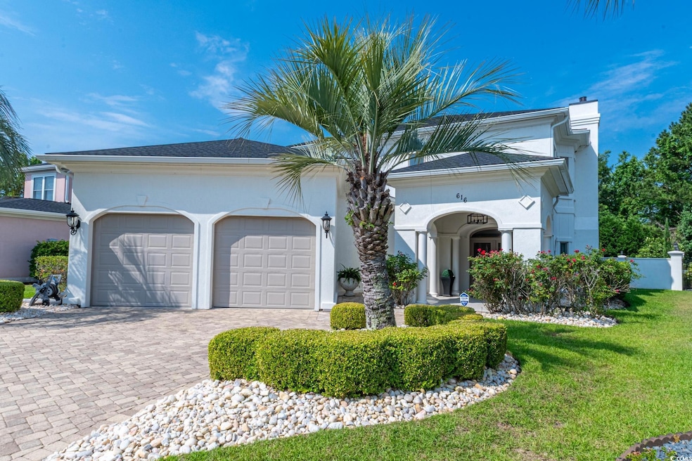 View of front facade featuring a chimney, a garage, decorative driveway, a front lawn, and stucco siding
