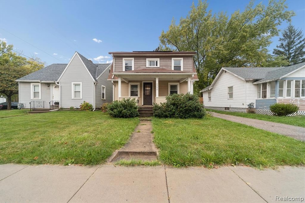View of front of house featuring a porch, a front lawn, and a shingled roof