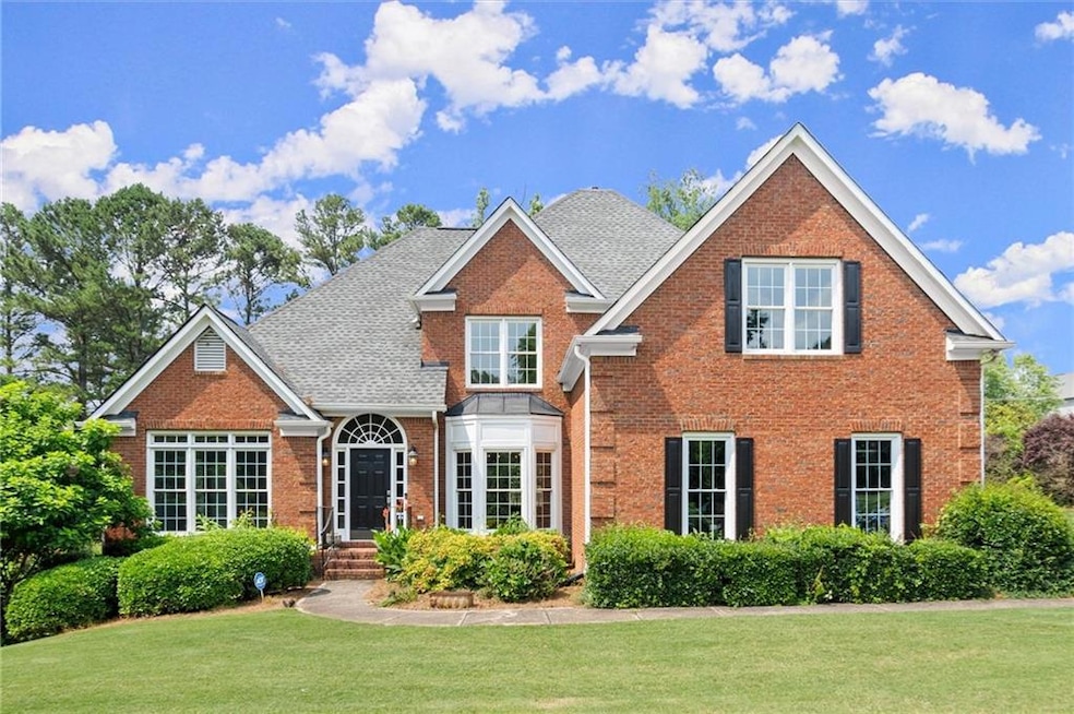 Traditional-style home with brick siding, a front lawn, and a shingled roof