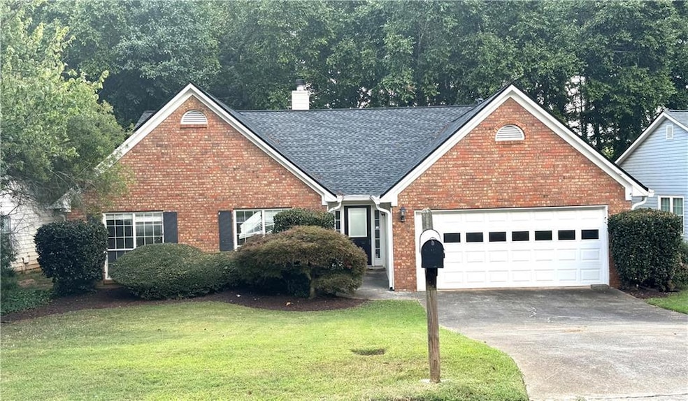View of front of house with driveway, a chimney, a front yard, and a garage