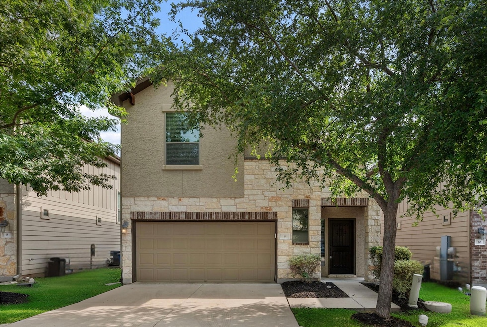 View of front facade with stone siding, a garage,