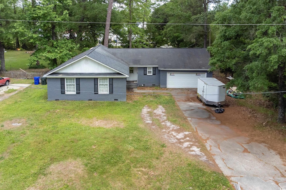 Single story home with a garage, fence, brick sidi