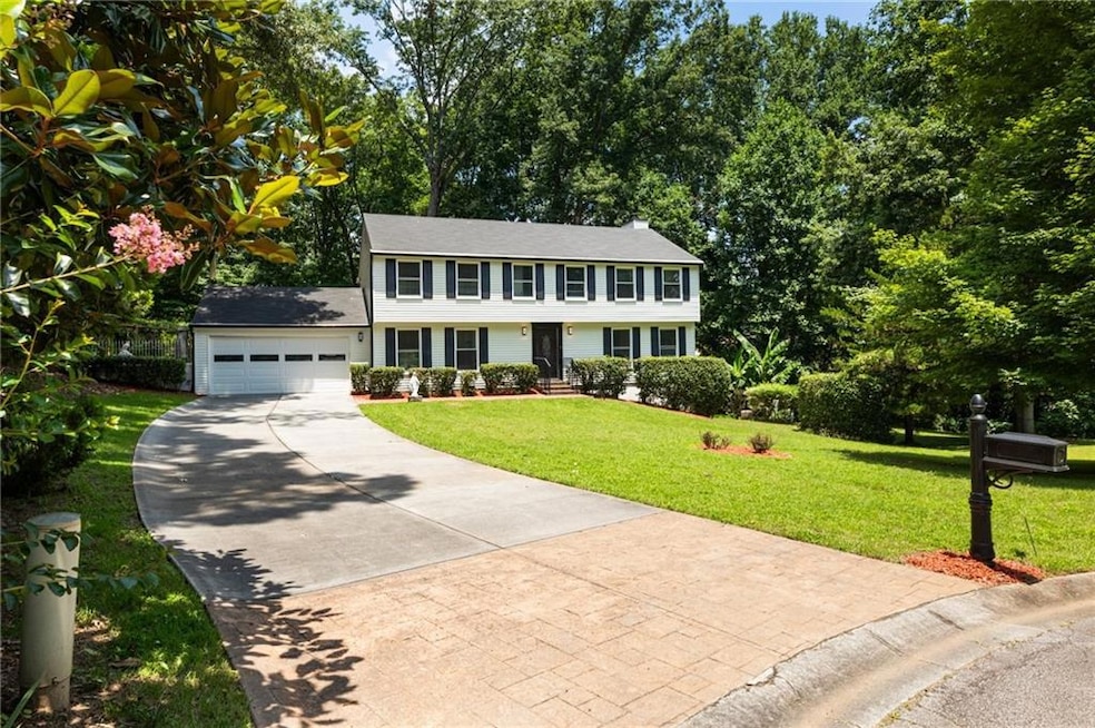 Colonial inspired home featuring concrete driveway, a garage, and a front yard