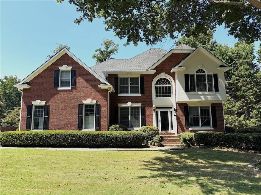 Colonial-style house with brick siding and a front lawn