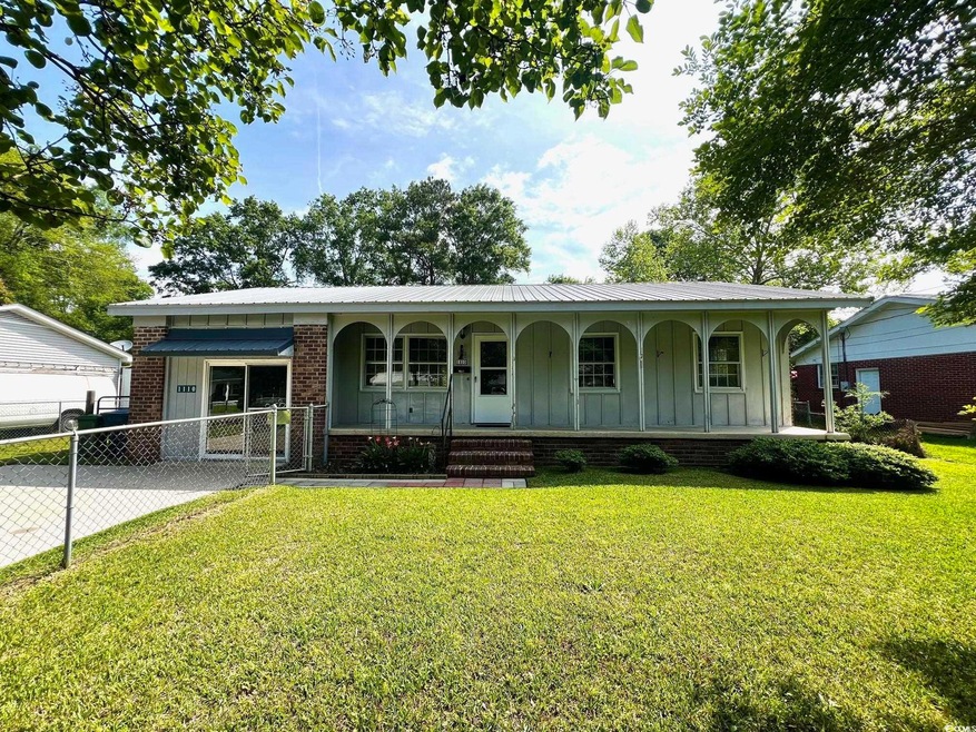 Single story home with board and batten siding, covered porch, a gate, fence, and a front yard