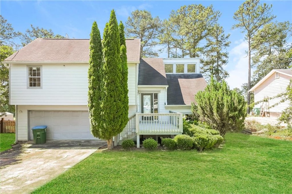 View of front of property featuring a shingled roof, a garage, concrete driveway, and a front lawn