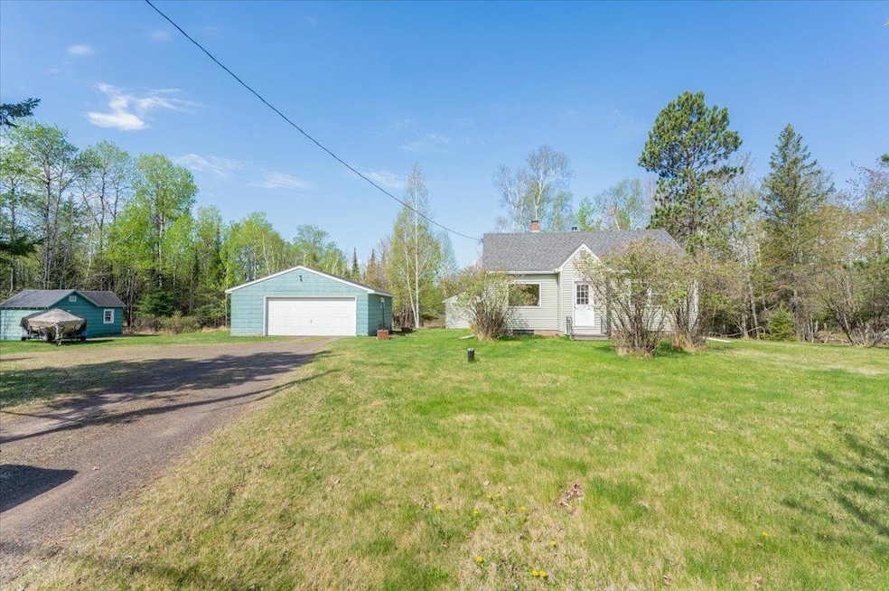 View of front of house with a garage, an outbuilding, and a front yard