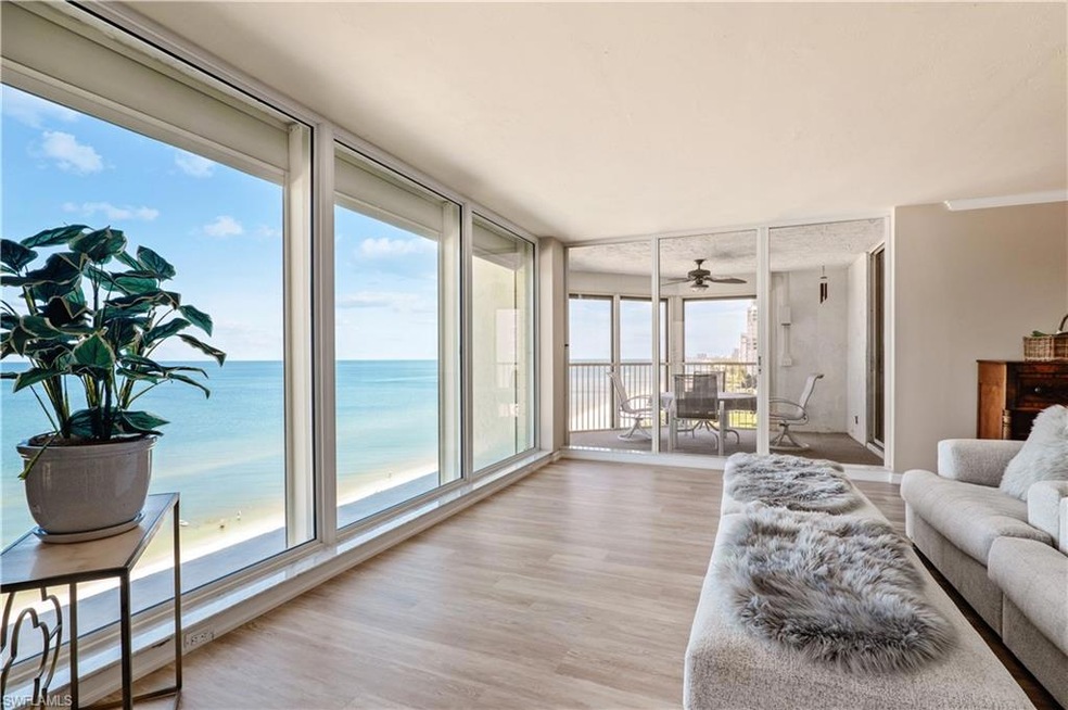 Living room featuring light wood-type flooring, a view of the Gulf of Mexico, a screened lanai with table and chairs