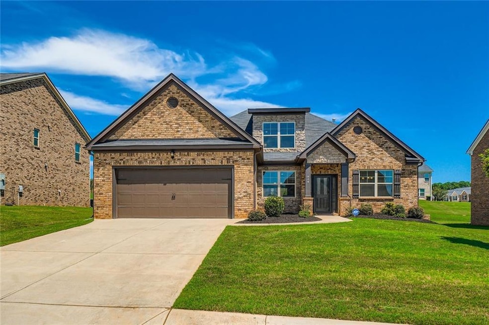 Craftsman-style house featuring a front lawn, driveway, an attached garage, brick siding, and stone siding