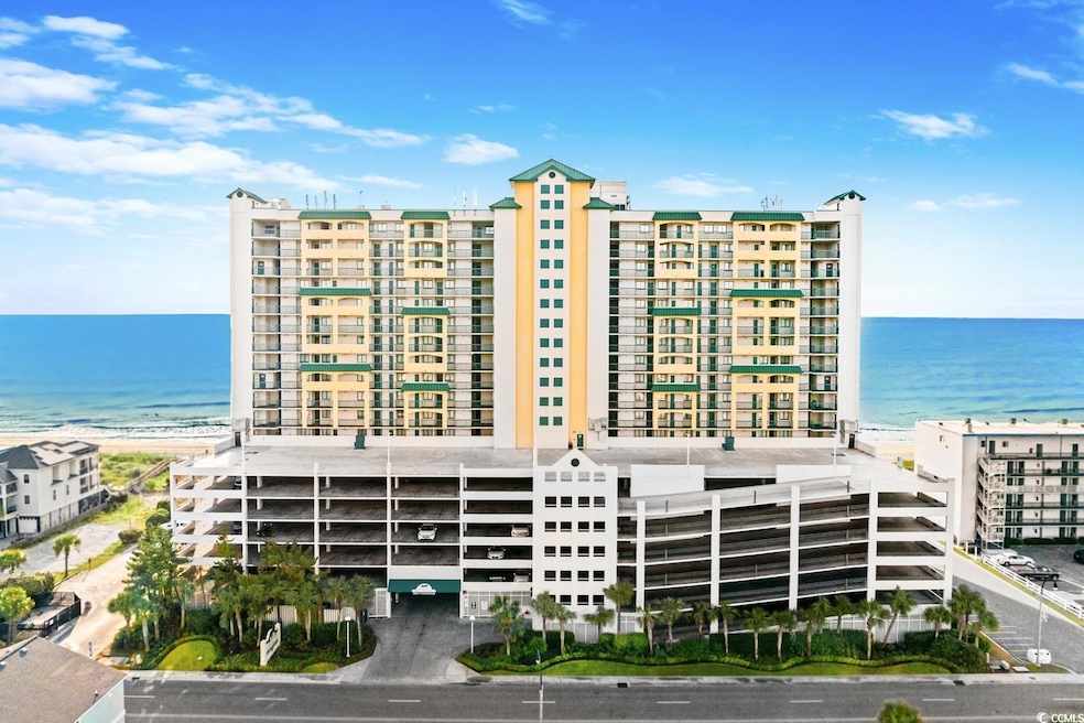 View of apartment building / complex featuring view of water and beach