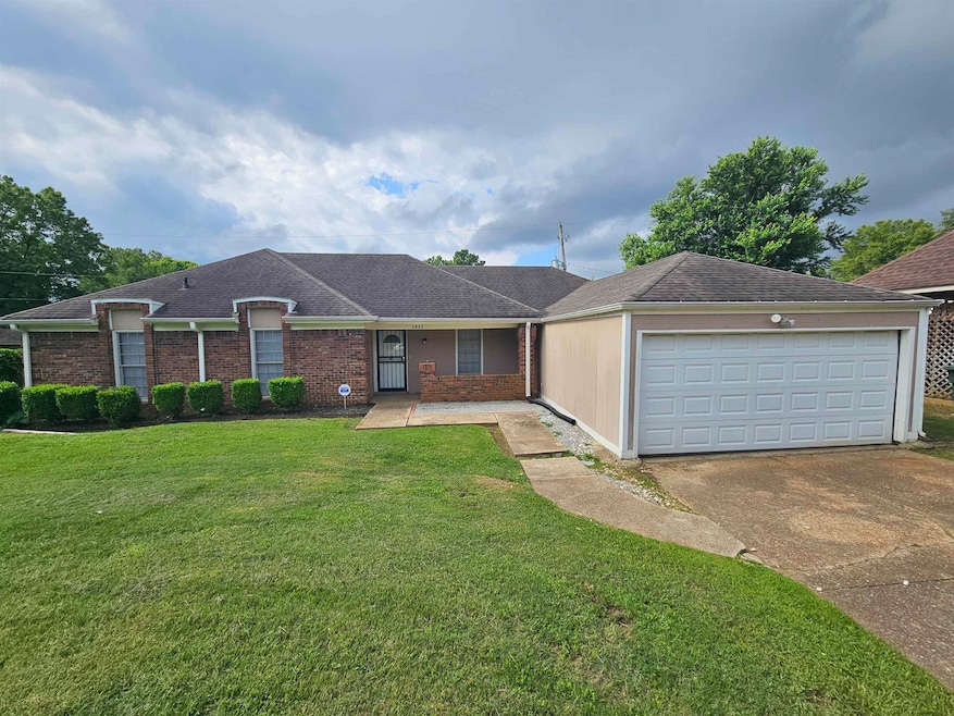 View of front of house with concrete driveway, a front lawn, a garage, roof with shingles, and brick siding