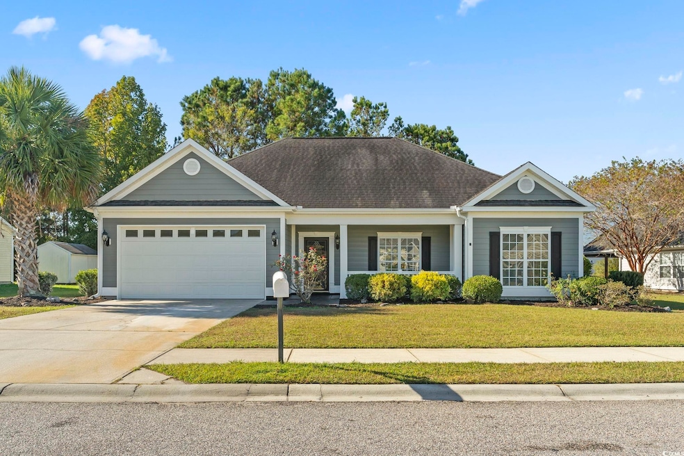 Ranch-style house featuring an attached garage, a front yard, driveway, and a shingled roof