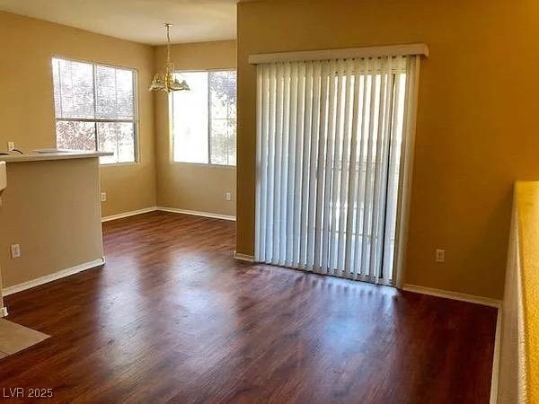 Spare room with dark wood-style flooring and a chandelier