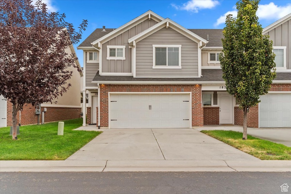 View of front facade with board and batten siding, driveway, a shingled roof, a front lawn, and a garage