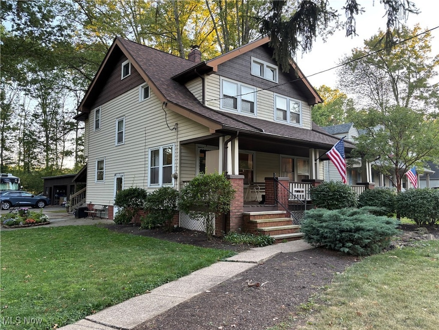 View of front of property with a front lawn, covered porch, a chimney, and roof with shingles
