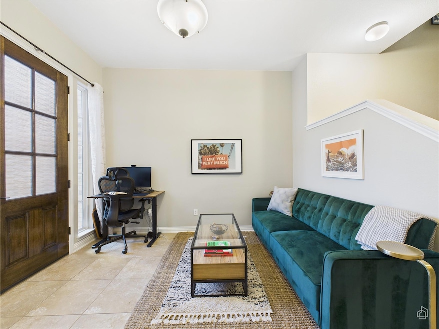 Living area featuring baseboards and light tile p